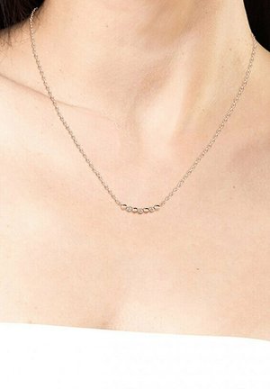 Collana in argento con un design curvo decorato da sei piccole perline tonde in oro e argento, posizionate centralmente lungo la catena.