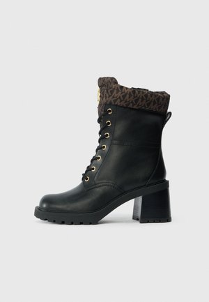 Bottine en cuir noir avec un revers marron à motifs, œillets dorés et un talon épais noir. Elle dispose d'une semelle robuste pour une meilleure adhérence.