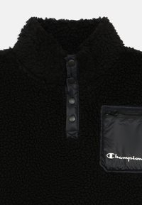 Pullover in pile nero con chiusura a scatto a quarto e taschino con zip sul petto, caratterizzato dal logo "Champion" bianco.