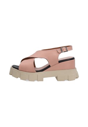 Pink leather sandal with cross-strap design, open toe, and adjustable ankle strap. Features a chunky beige platform sole with textured detail.
