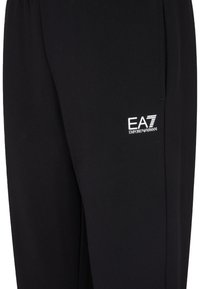 Pantaloni sportivi neri realizzati in tessuto morbido, con una vestibilità affusolata e un piccolo logo EA7 bianco sul lato inferiore.