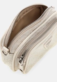 Piccola borsa a tracolla color crema realizzata in tessuto testurizzato, con due scomparti con zip, hardware in argento e un design liscio e strutturato.