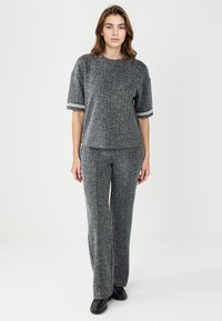 Ensemble tricoté en deux pièces gris et noir comprenant un haut à manches courtes avec des finitions décoratives et un pantalon évasé assorti.