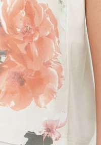 Tejido con estampado floral que presenta grandes rosas melocotón sobre un fondo suave y claro. Textura lisa con una calidad ligeramente translúcida y bordes cosidos.