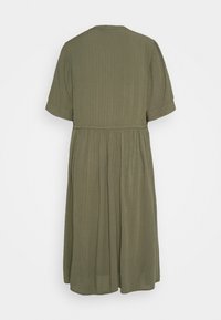 Olivia grön midi-klänning med korta ärmar, ribbad textur, figurnära midja och ett flödande kjol, med en enkel rund halsringning.