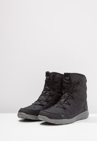 Schwarze halbhöhe Wanderschuhe aus Textil und synthetischem Material, mit strukturierter Oberfläche, Schnürverschluss und Gummisohle.