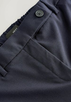 Navy trousers with a smooth texture, featuring a button closure and elastic waist. Includes top-stitched pockets and a brand label, "NEXT."