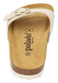 Vit halksandaler med ett enda rem och spänne, som har en beige dämpad sula och en korksula; "palado"-logotyp präglad inuti.