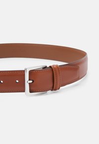 Cinturón de cuero marrón, textura suave, con hebilla de metal plateado, ajuste regulable con cinco agujeros y detalles de costura en contraste.