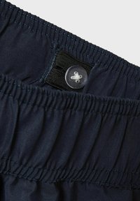 Shorts elasticizzati blu navy con chiusura a bottone, realizzati in un tessuto leggero e liscio e con una texture arricciata in vita.
