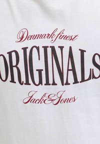 Camiseta blanca de algodón con texto en negrita negro y burdeos: "Los mejores ORIGINALS de Dinamarca Jack&Jones," con una mezcla de fuentes en serif y script.