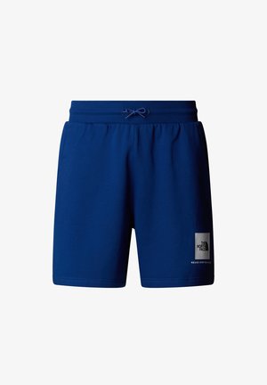 Pantalones cortos de algodón azul con cintura elástica y cordón. Cuenta con un parche de logo en la pierna izquierda. Textura suave, diseño hasta la rodilla.