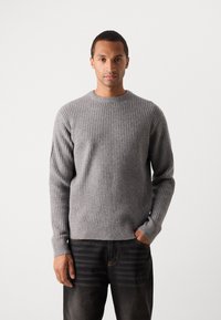 Gray ribbed sweater with a round neck, long sleeves, and a fitted waistband. The fabric has a soft texture and subtle pattern.