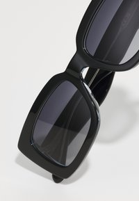 Óculos de sol retangulares pretos com uma armação robusta, lentes escuras, acabamento brilhante e hastes grossas. Design simples sem padrões ou acentos notáveis.