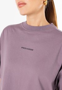 Lavanda pamučna dukserica s okruglim izrezom, s crnim "PEGADOR" logotipom na gornjem lijevom dijelu grudi. Glatka tekstura i opušten kroj.