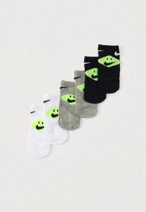 Set aus fünf Knöchelsocken mit einem fröhlichen Gesicht als Grafik. Farben umfassen Weiß, Grau und Schwarz, mit neon-grünen Akzenten und Nike-Logo.