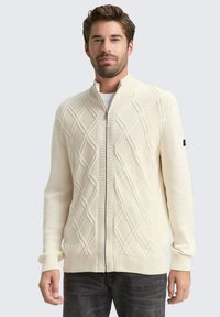 Cremfarbenes Zip-Cardigan mit strukturiertem Rautenmuster, gerippten Bündchen und Saum. Der Stoff wirkt gestrickt, lässiges Design.