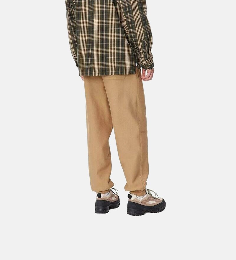 Chemise à carreaux en vert foncé et beige, associée à un pantalon beige fuselé et des baskets noires volumineuses avec un dessus texturé et des lacets.