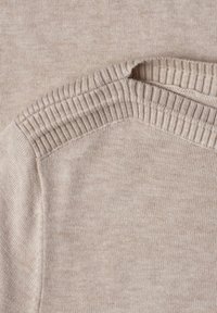 Pull beige en laine avec détail de col côtelé, mettant en valeur une texture douce et un gros plan de l'épaule et de l'encolure.