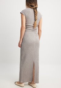 Siva, rebrasta maksi obleka s kratkimi rokavi, prilegajočim topom in stranskim razporkom. Gladka tekstura, sproščen dizajn, mešanica tkanin in dolžina do gležnjev.