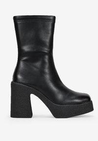Bottines en cuir noir avec un bout arrondi et une hauteur mi-mollet, présentant un talon chunky texturé et une plate-forme. Design épuré et minimaliste.