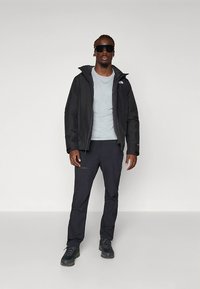 Črno vodoodporno jakno z visokim ovratnikom, sivo majico in temne hlače. Tkanina z teksturo in poudarki etikete. Črni pohodni čevlji za popoln videz.