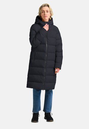 Cappotto lungo nero in piuma con cappuccio, caratterizzato da sezioni trapuntate e una cerniera frontale. Indossato sopra jeans blu e scarpe nere.
