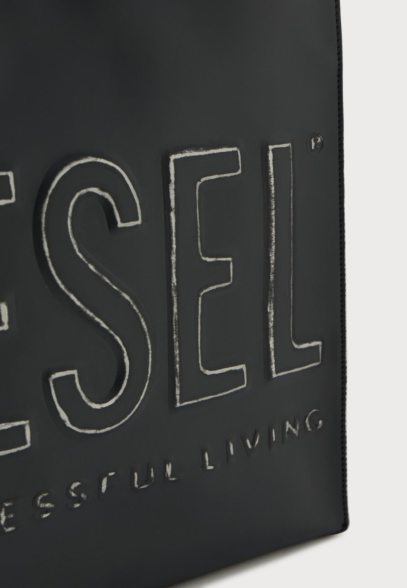 Borsa a tracolla nera con logo "DIESEL" in rilievo e testo "SUCCESSFUL LIVING". Texture liscia, materiale resistente e cuciture curate lungo i bordi.