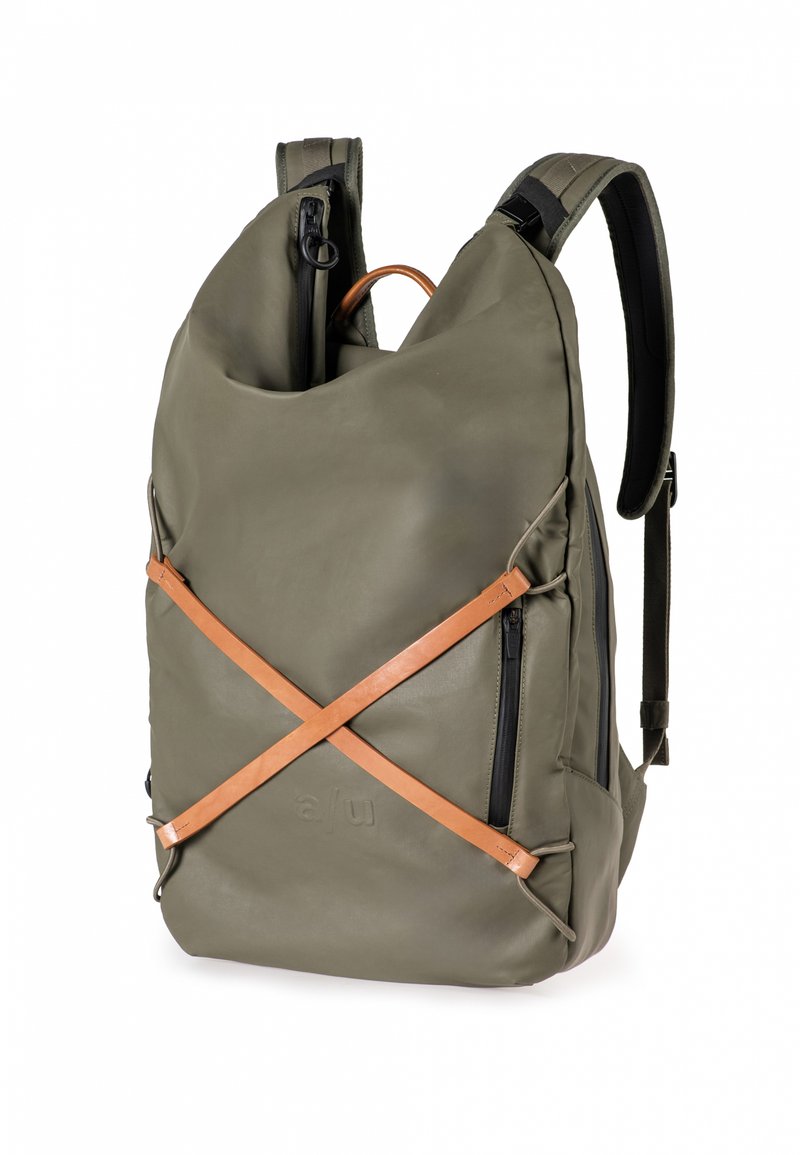 Zaino verde oliva realizzato in materiale testurizzato, con una tracolla in pelle marrone chiaro, tasche con zip e spallacci regolabili.