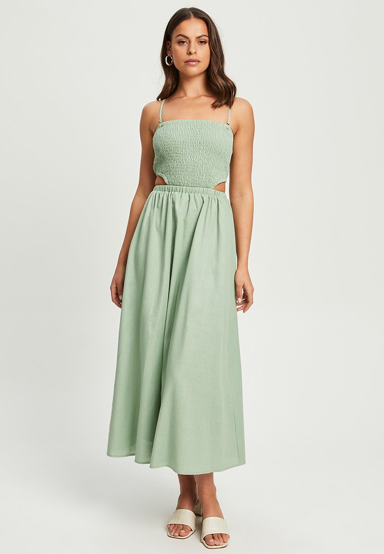 Mintgrøn maxi-kjole med smocket bodice, tynde stropper, sideudskæringer og en let skørt. Tekstureret stof og samlet talje detalje.