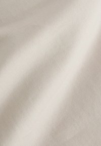 Világosbézs textúrájú szövet, finom bordázott mintával, amely puha, sima felszínnel és lágy redőkkel rendelkezik. Kárpitozáshoz vagy ruházathoz megfelelő.