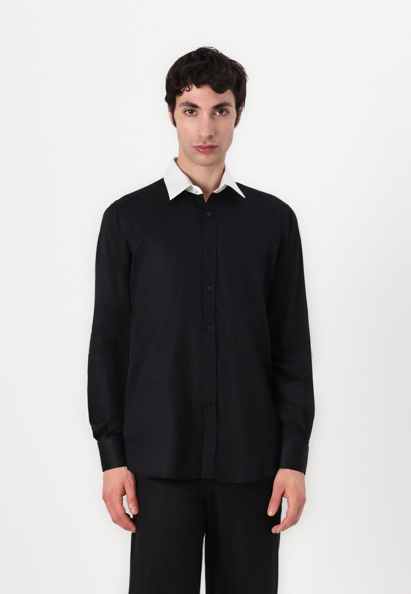 Svart langermet skjorte med en kontrastfylt hvit krage, knapp-ned design, og lett tekstur. Har en avslappet passform og minimalistisk stil.