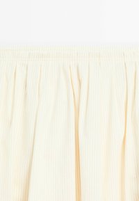 Jupe beige clair avec des rayures verticales, dotée d'une taille élastique froncée et d'une texture douce. Le tissu présente un léger éclat.