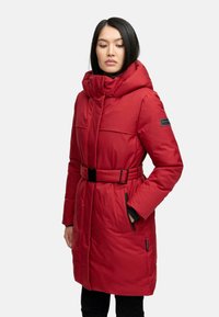 Red padded coat with a high collar, belted waist, and zippered pockets. Features a smooth texture and logo accent on the sleeve.
