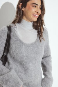 Gray fuzzy knit sweater with a scoop neckline and long sleeves, layered over a white turtleneck. Black shoulder strap bag visible.