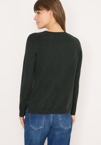 Dunkelgrüner Strickpullover mit langen Ärmeln, runder Ausschnitt und Seitenschlitzen. Aus weichem, strukturierter Stoff für Komfort gefertigt.