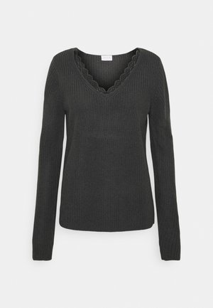 Svart stickad tröja med långa ärmar, V-ringning och scallopkant längs ringningen. Medelvikts och texturerat tyg.