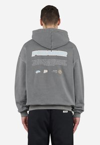 Grå sweatshirt med hætte, prydet med stort "PEGADOR"-tekst og beskrivende print på ryggen. Ribstrikkede manchetter og kant for god pasform.