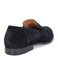 Granatowe zamszowe buty wsuwane z okrągłym noskiem i niską czarną gumową podeszwą. Wnętrze ma beżową podszewkę oraz minimalne detale w szwach.