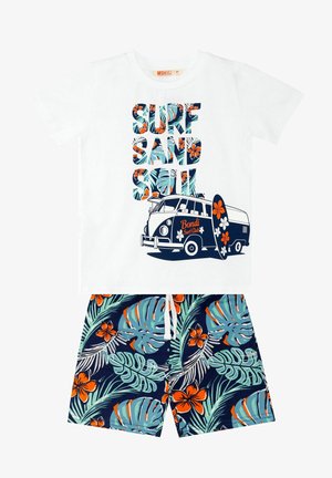 T-shirt bianca con stampa blu e arancione "SURF SAND SOUL", con un grafico di un furgone vintage. Abbinata a shorts blu scuro con motivo di foglie tropicali e fiori arancioni.