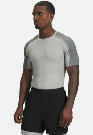 Kurzärmliges Sportshirt in Hellgrau mit strukturiertem Stoff. Es hat ein figurbetontes Design mit kontrastierenden dunkelgrauen Akzenten und einem runden Ausschnitt.