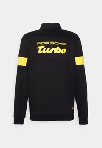 Chaquetón negro de manga larga con texto amarillo "Porsche turbo" en la parte trasera y bandas amarillas en las mangas superiores, puños acanalados y cuello.