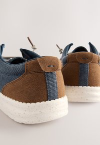 Blauer Stoff- und brauner Wildledersneaker mit weiß gesprenkelter Sohle. Verfügt über eine Zuglasche, kontrastierende Textur und minimalistisches Design.
