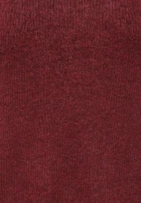 Burgunderrote Strickware mit einer weichen, strukturierten Oberfläche. Das Material zeigt eine feine, gleichmäßige Webart und reflektiert das Licht mit einem dezenten Glanz.