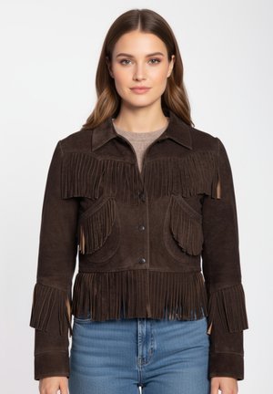 Donna che indossa una giacca in suede marrone scuro con dettagli a frange su petto, tasche, polsini e orlo, abbinata a jeans azzurri.