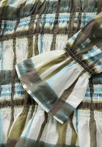 Rochie din bumbac în nuanțe de verde, maro și albastru. Are textură adunată, model cu dungi și mâneci bufante cu mansete elastice.