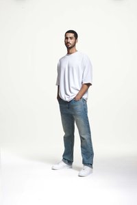 Balta trumpa rankovė t-shirt, derinama su šviesiai mėlynomis džinsinėmis kelnėmis. Modelis dėvi baltus sportinius batelius. Paprastas, kasdienis dizainas su laisvu siluetu.