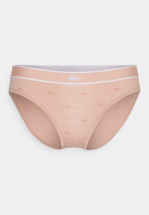 Rozā kokvilnas biksītēm ar baltu elastīgu jostu. Ievērojams Lacoste logo un atkārtoti mazi logo gaišākā tonī. Gluda tekstūra.