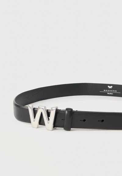 Μαύρη δερμάτινη ζώνη με ασημί μεταλλική αγκράφα σε σχήμα "W". Ομαλή υφή με τρύπες για ρύθμιση· το λογότυπο της μάρκας είναι ανάγλυφο στην κάτω πλευρά.
