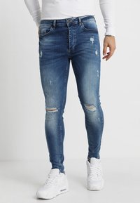 Smala jeans i ljusblå denim med slitna detaljer, blekta lappar och två knäsprickor. Designen inkluderar en klassisk femficksstil.